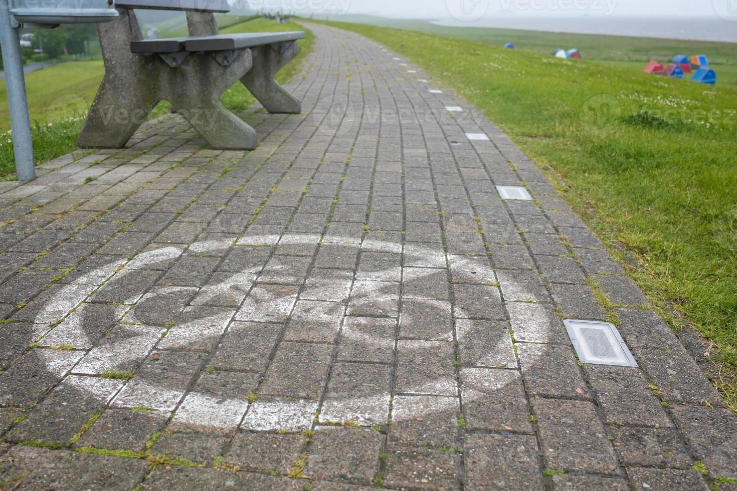 sentier en pierre avec un panneau interdisant le vélo peint dessus, sur fond de banc. notion de sécurité. photo