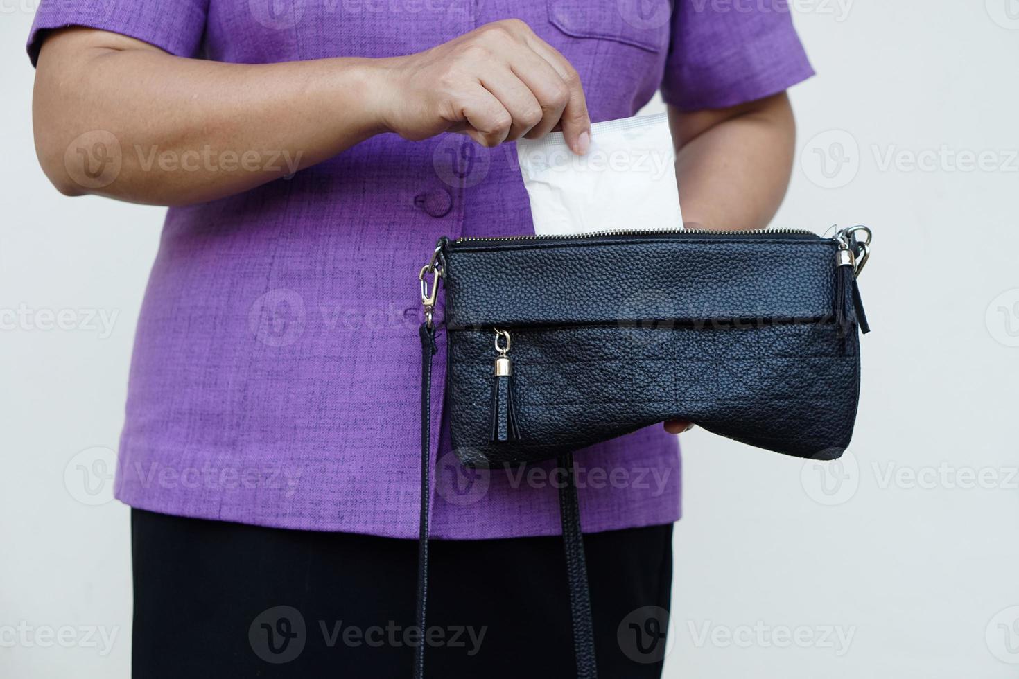 la femme en gros plan tient une serviette hygiénique pour la menstruation à mettre dans un sac avant de sortir. concept, hygiène féminine, produit enic pour le jour de la période. santé de la femme. Hygiène intime mensuelle. photo