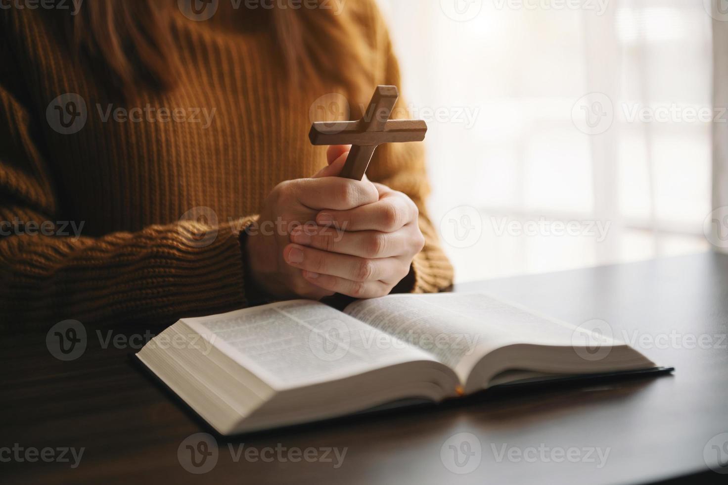 femme assise et étudiant les écritures.la croix de bois dans les mains. concepts d'éducation chrétienne les saintes écritures s'ouvrent et prient photo