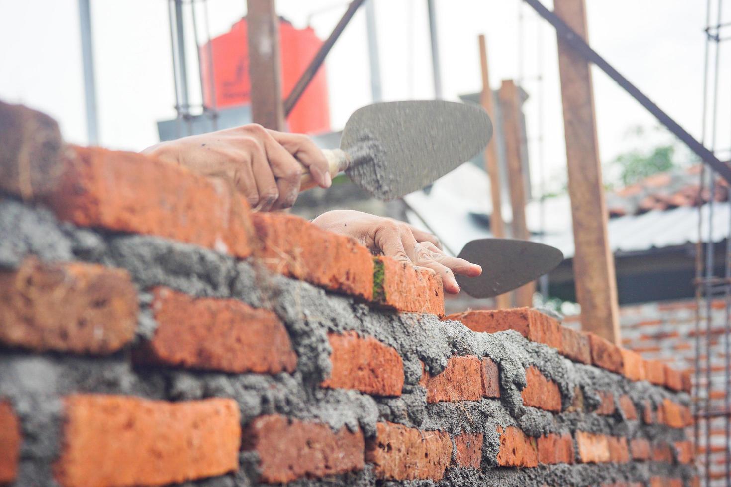 les ouvriers du bâtiment installent des briques et du ciment à partir de rangées de briques sur les murs extérieurs photo