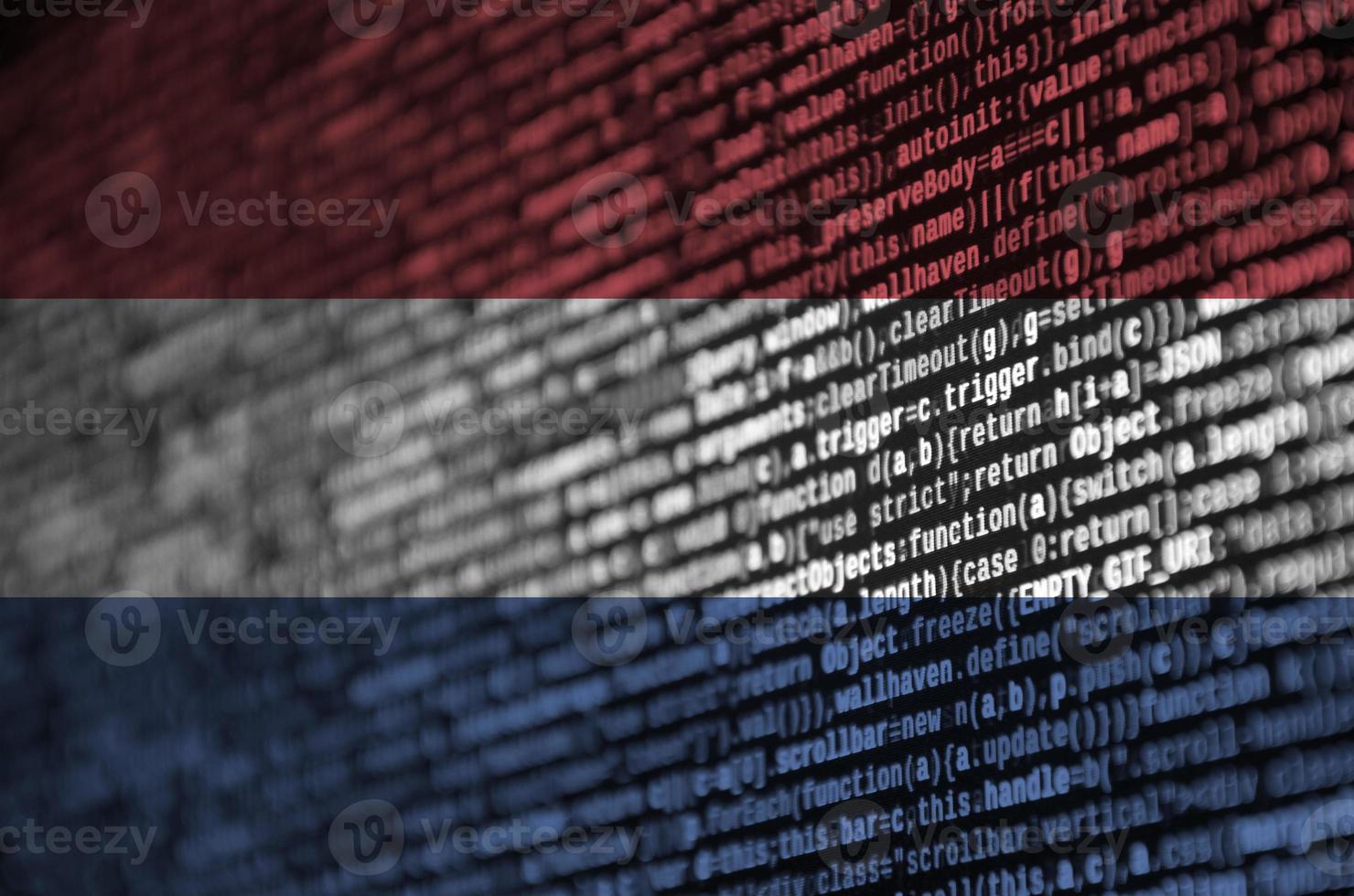 drapeau néerlandais est représenté sur l'écran avec le code du programme. le concept de technologie moderne et de développement de site photo