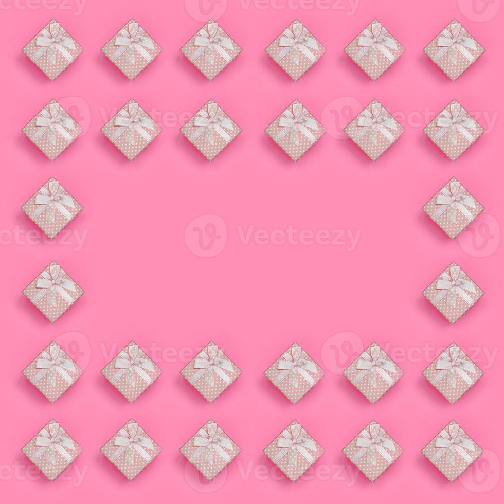 cadre de coffrets cadeaux roses se trouve sur fond de texture de papier de couleur rose pastel de mode dans un concept minimal. motif tendance abstrait photo