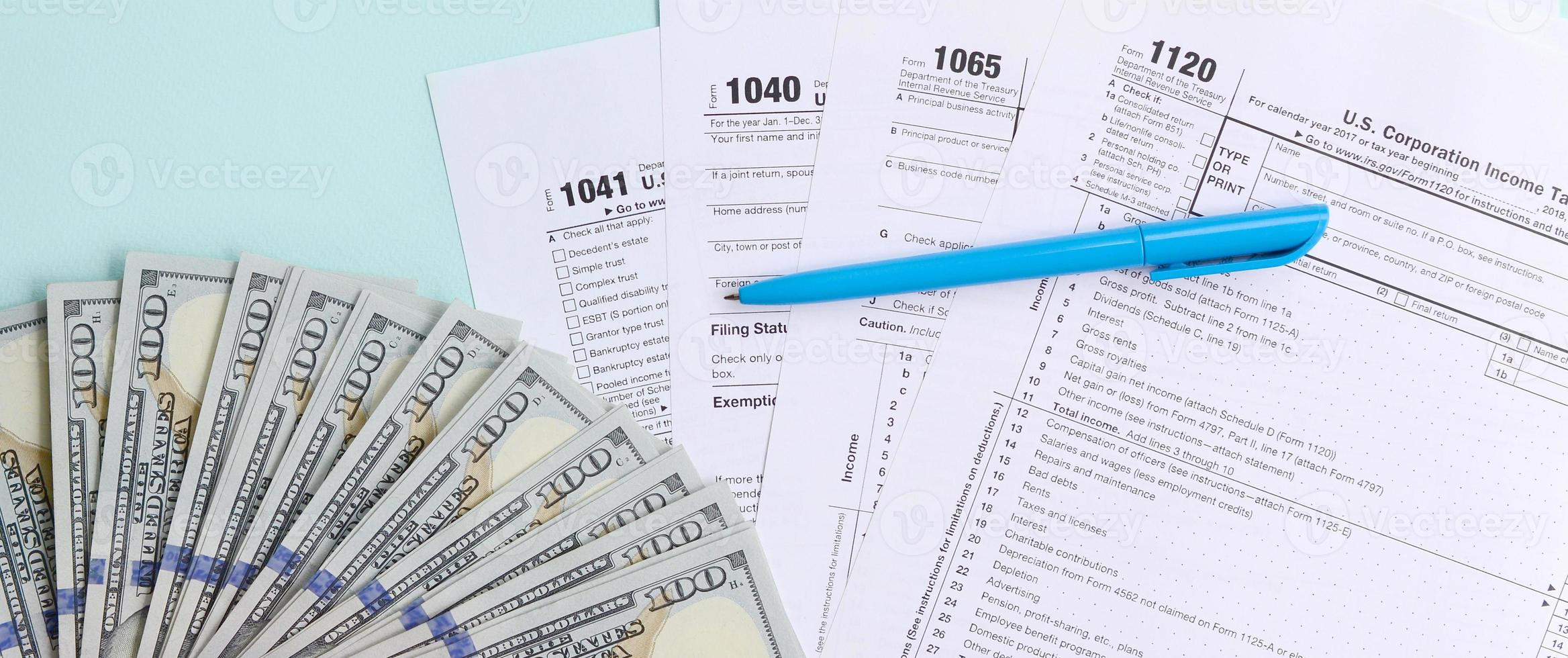 les formulaires fiscaux se trouvent près de billets de cent dollars et d'un stylo bleu sur fond bleu clair. déclaration d'impôt sur le revenu photo
