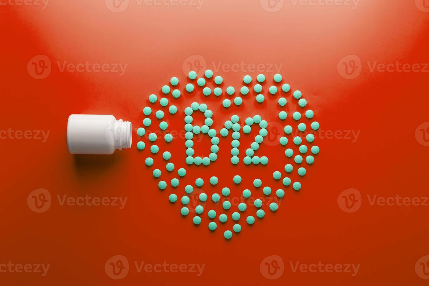 vitamines b 12 en forme de coeur sur un substrat rouge, versées d'un pot blanc. photo