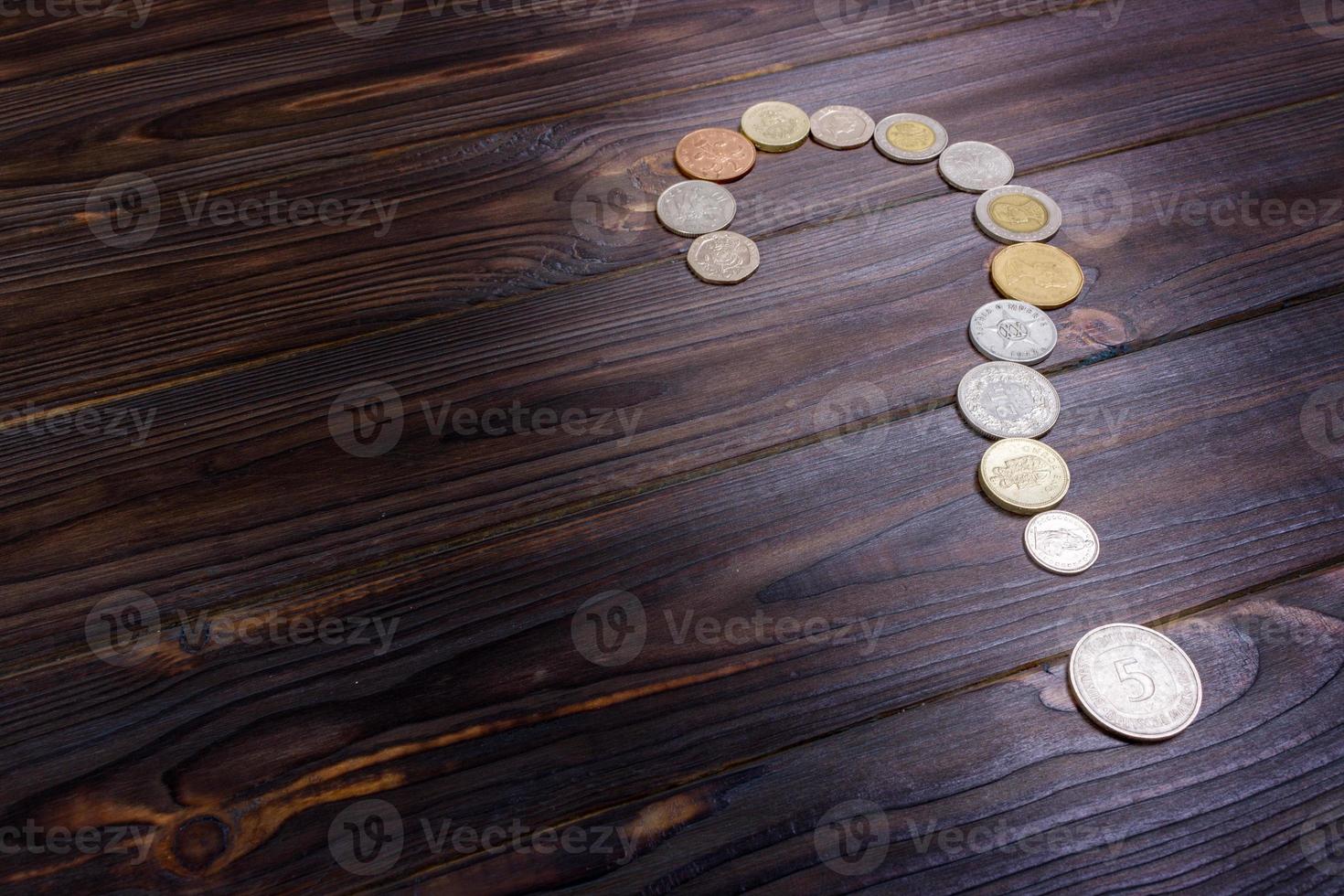 point d'interrogation des pièces de monnaie de différents pays sur un fond en bois photo