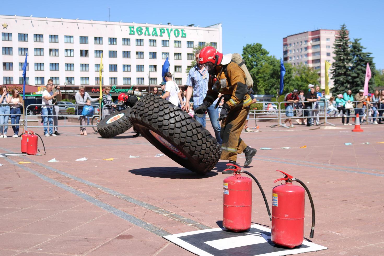 un pompier dans une combinaison ignifuge et un casque court et tourne une grande roue en caoutchouc dans un concours de lutte contre l'incendie, biélorussie, minsk, 08.08.2018 photo