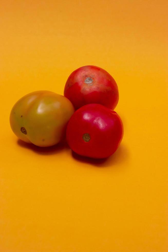 trois tomates isolées sur jaune photo