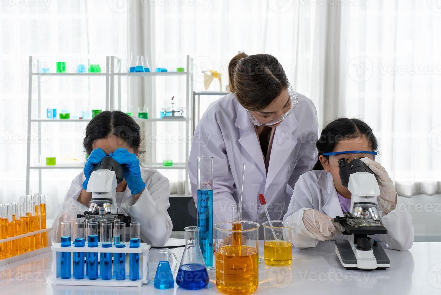 enfants utilisant un microscope pour apprendre la microbiologie et la science en laboratoire avec un enseignant photo