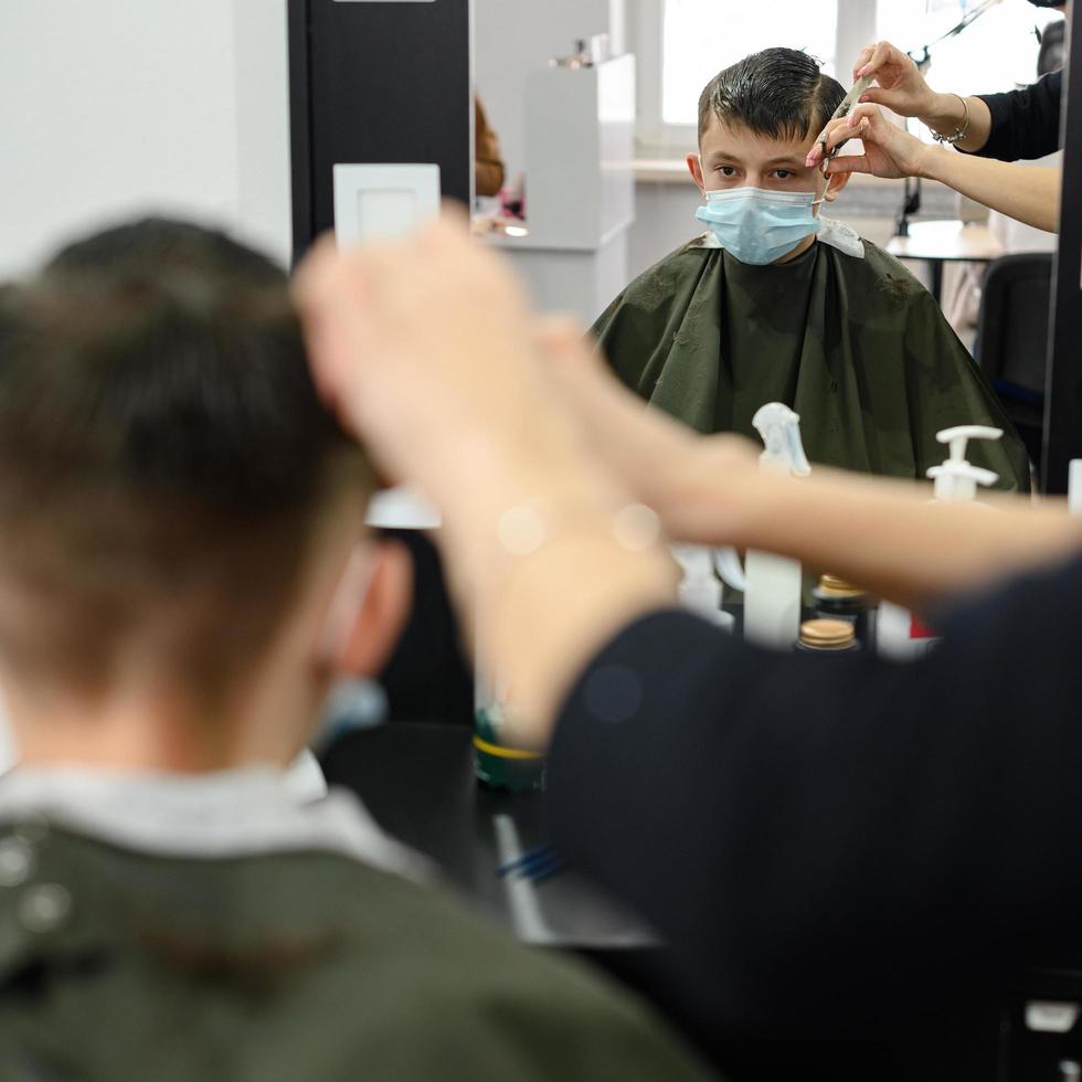 un adolescent dans un salon de beauté se fait couper les cheveux, un coiffeur coupe les cheveux d'un adolescent. photo