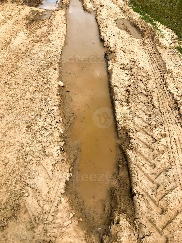 texture d'un chemin de terre sale et sale avec des flaques d'eau et de la boue de séchage d'argile avec des fissures et des ornières. hors route. l'arrière-plan photo