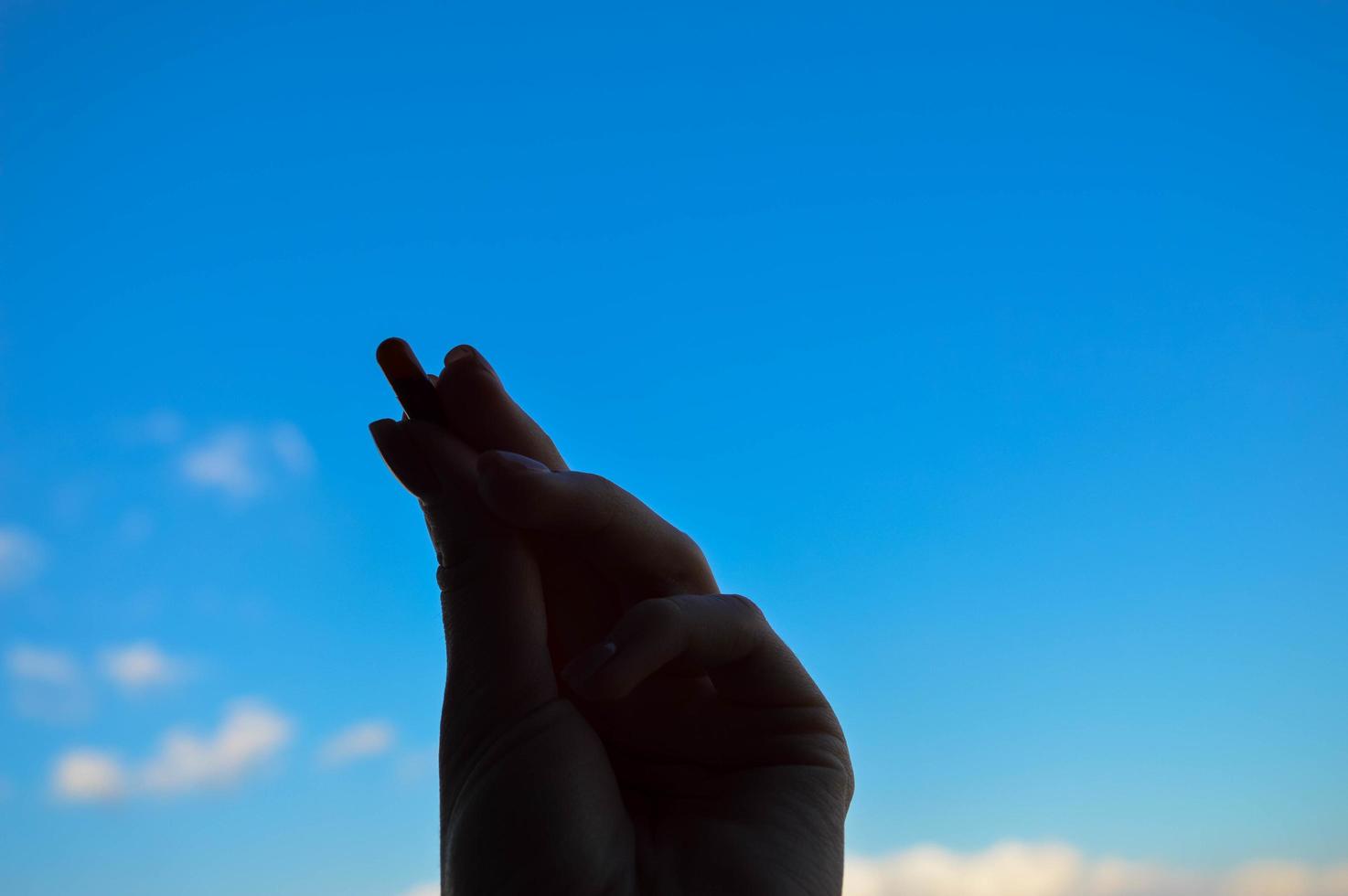 belle main féminine tient une capsule de pilule pharmaceutique médicale du coronavirus covid-19 pour le traitement des maladies et des virus sur fond de ciel bleu photo