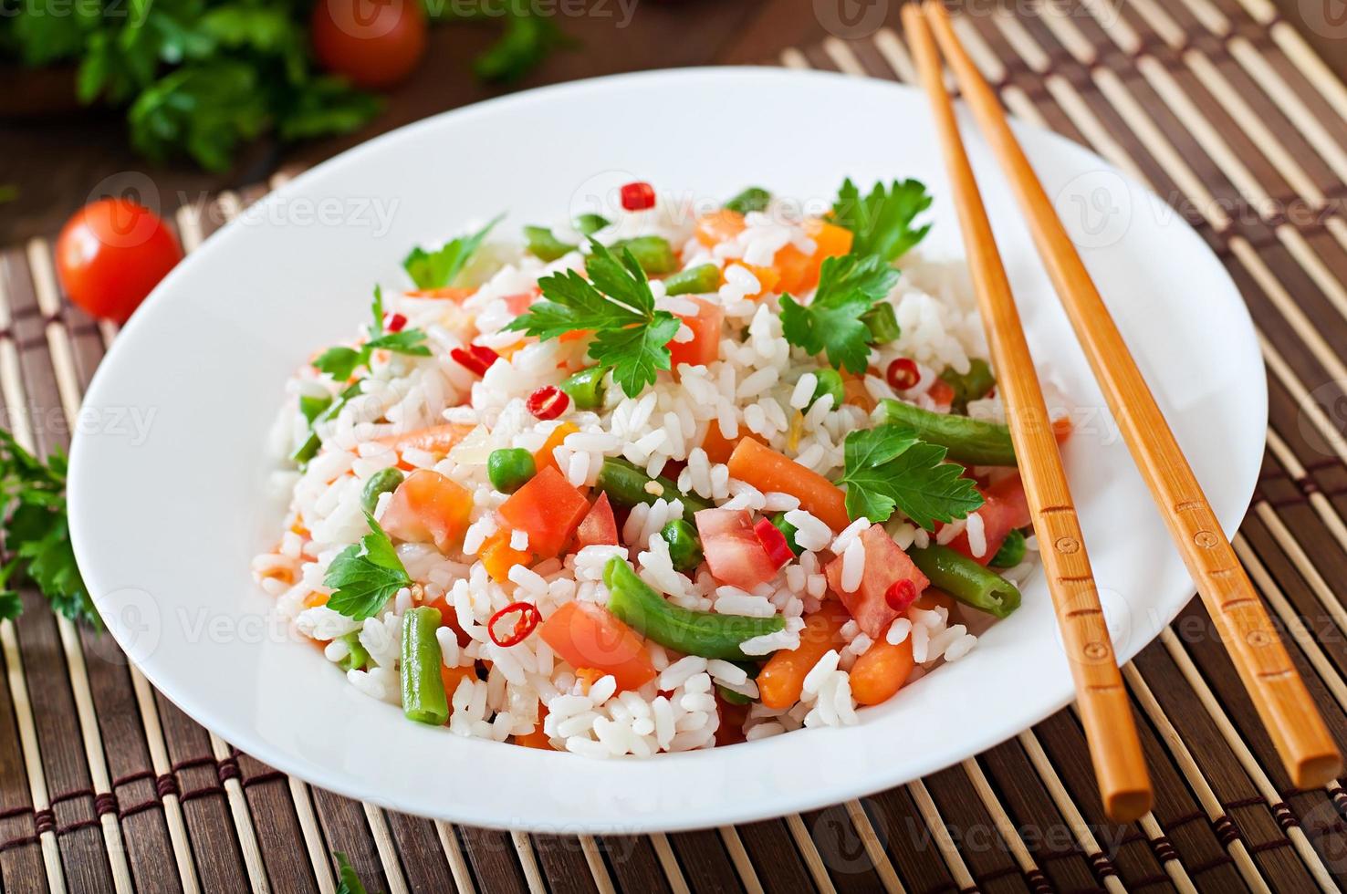 riz sain appétissant avec des légumes dans une assiette blanche sur un fond en bois. photo