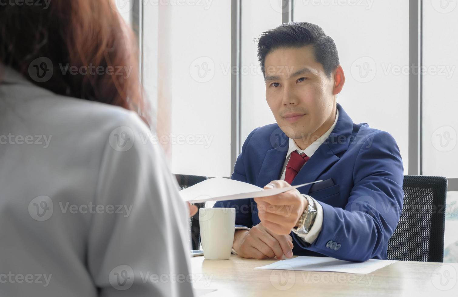 homme d'affaires cadre supérieur au visage sérieux donnant du papier à une jeune femme au bureau. concept de recrutement, résiliation du concept de crise économique. photo