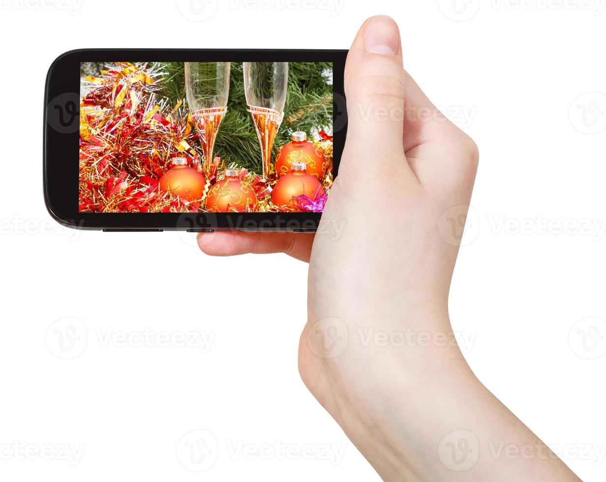 Main tient le téléphone portable avec Noël nature morte photo