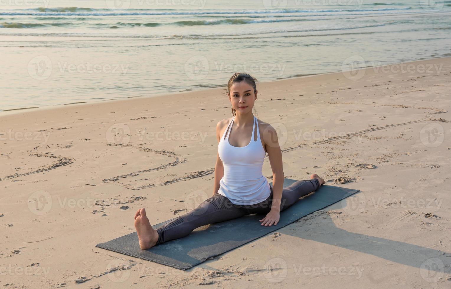 jeune femme asiatique en bonne santé faisant des exercices de yoga sur la plage le matin. photo