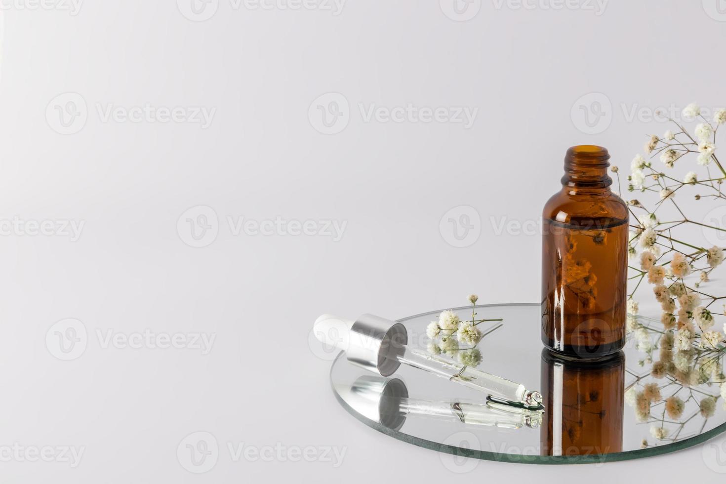 une bouteille ouverte avec de l'huile cosmétique naturelle ou un sérum pour les soins de la peau bio se dresse sur un miroir rond avec une pipette remplie. un espace de copie. photo