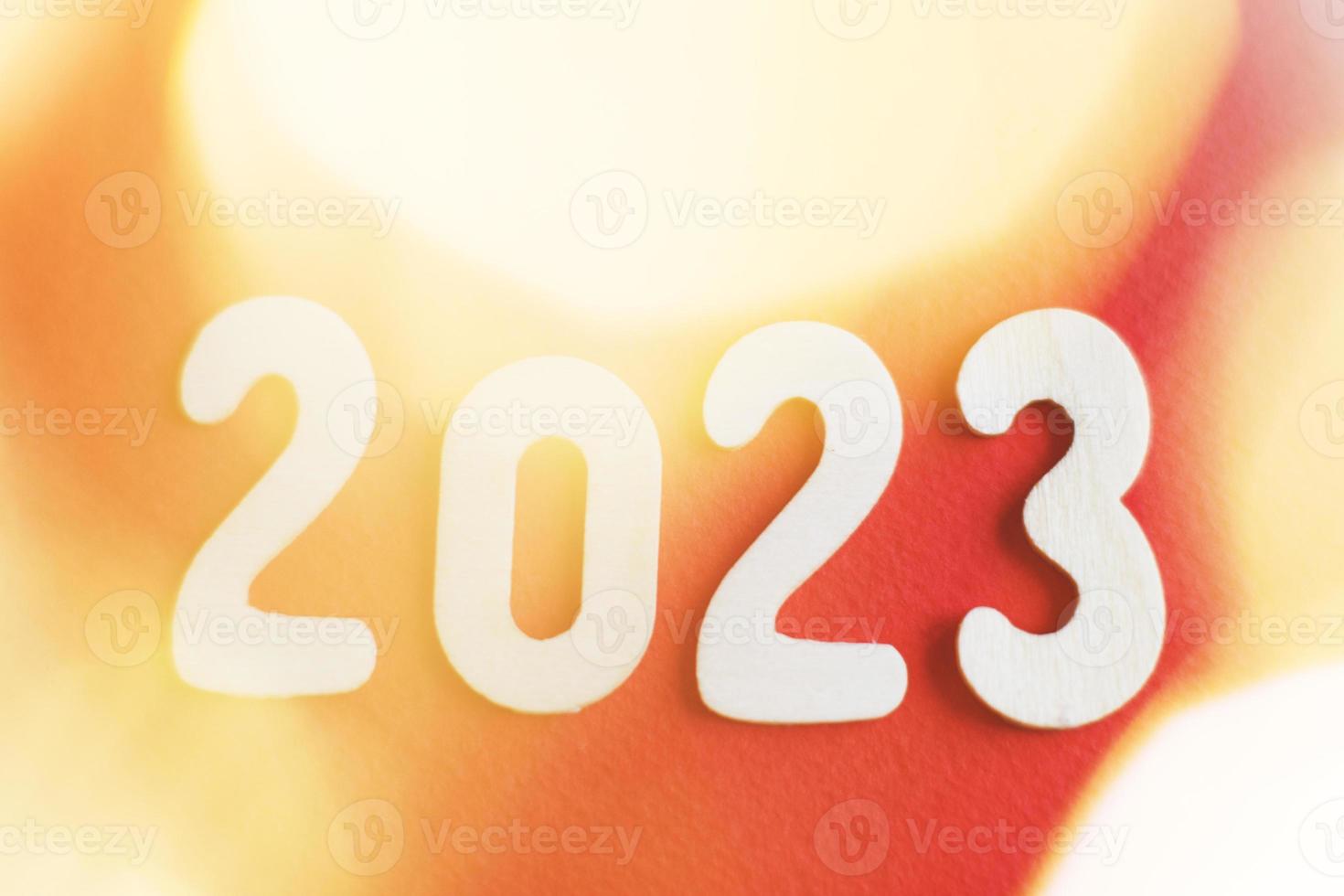 numéro en bois 2023 sur fond rouge et or brillant de noël. bokeh flou festif scintillant photo