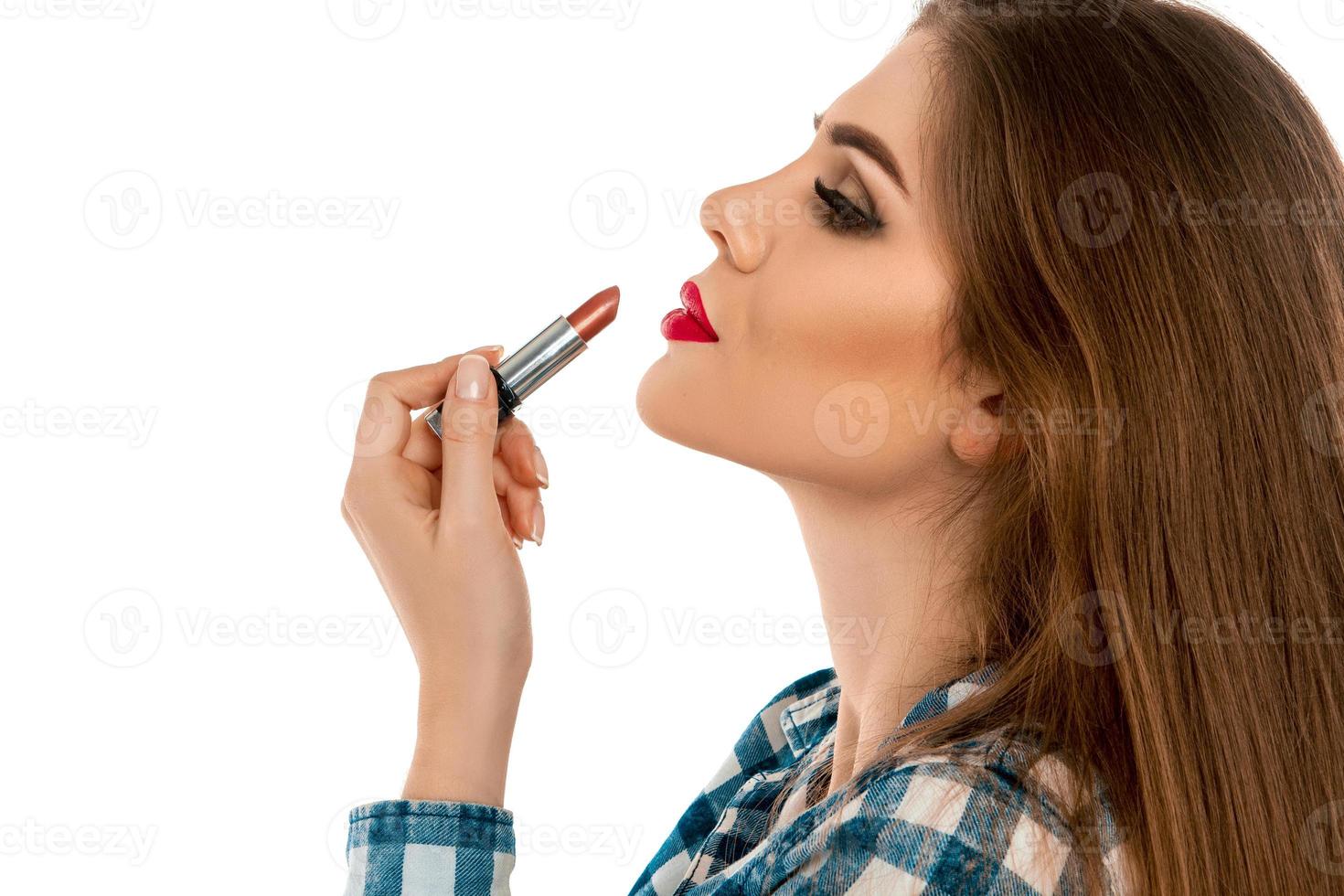 Portrait de profil de belle jeune fille avec du rouge à lèvres à la main photo