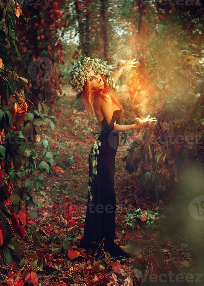 photo verticale d'une formidable sorcière rousse évoque dans les bois