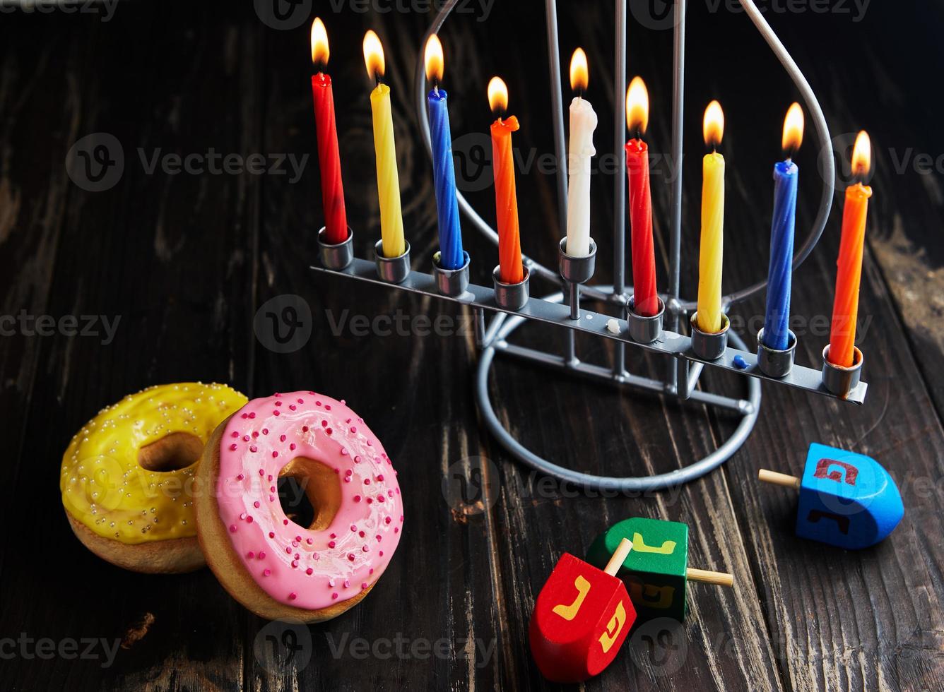 fond de hanukkah fête juive. un plat traditionnel est les beignets sucrés. table de hanukkah chandelier avec bougies et toupies sur fond noir. allumer des bougies de 'Hanoucca. copie espace photo