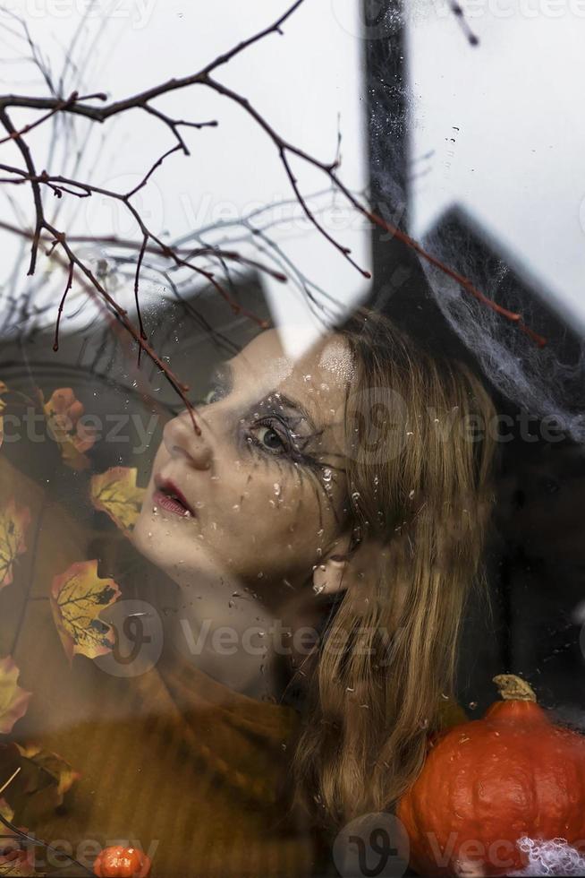 femme sorcière effrayante à l'extérieur de la fenêtre sur le fond des décorations d'halloween. mascarade, fête d'halloween photo