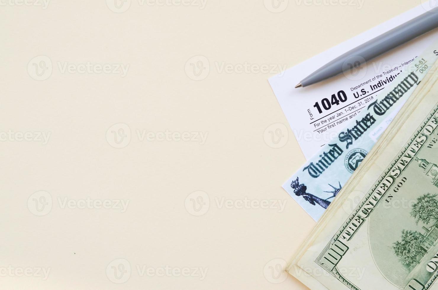 1040 formulaire de déclaration de revenus des particuliers avec chèque de remboursement et billets de cent dollars sur fond beige photo