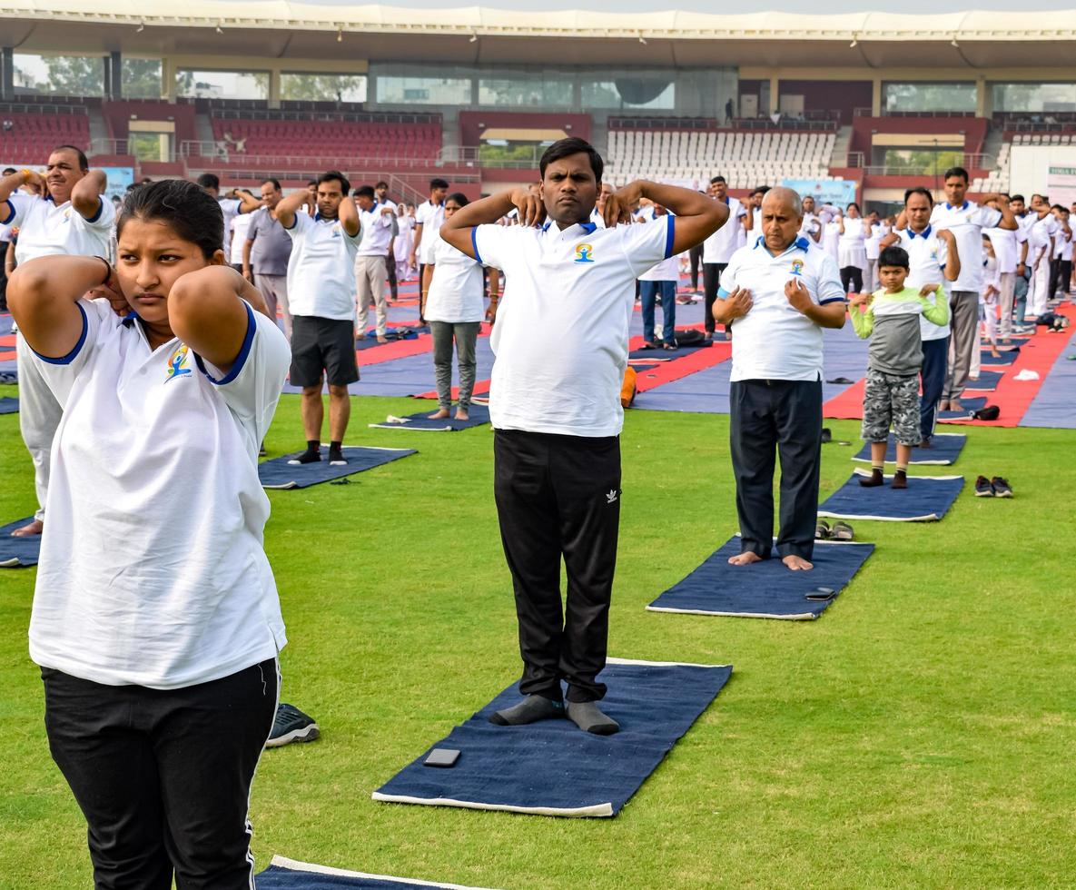 new delhi, inde, 21 juin 2022 - séance d'exercices de yoga en groupe pour les personnes du complexe sportif de yamuna à delhi lors de la journée internationale du yoga, grand groupe d'adultes assistant à un cours de yoga au stade de cricket photo