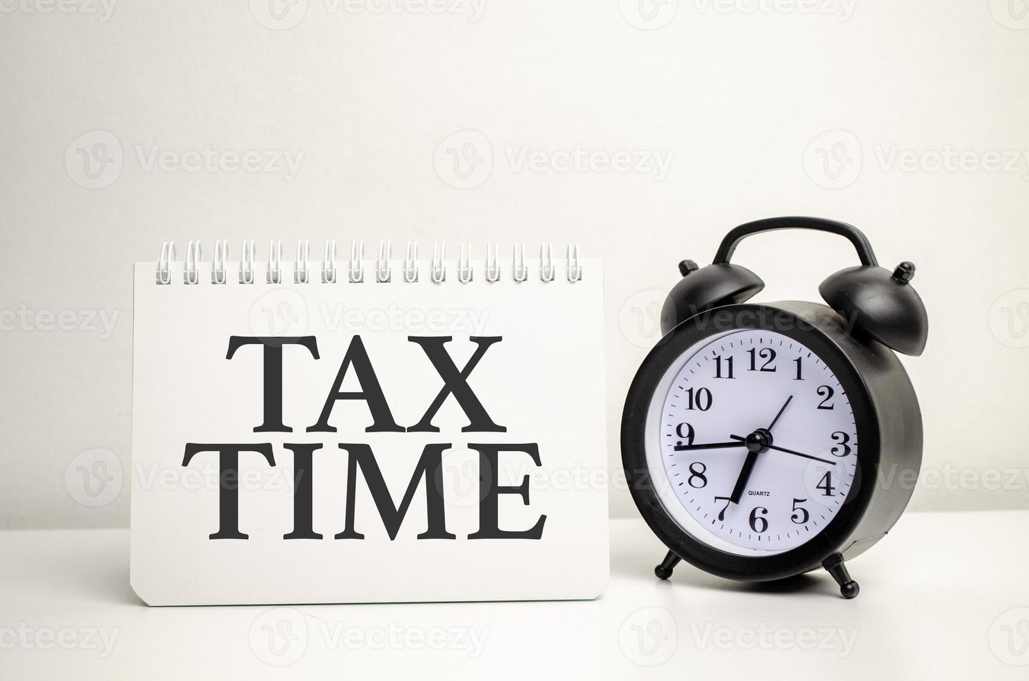 texte de typographie de temps d'impôt sur carte papier avec réveil et calculatrice sur fond blanc photo