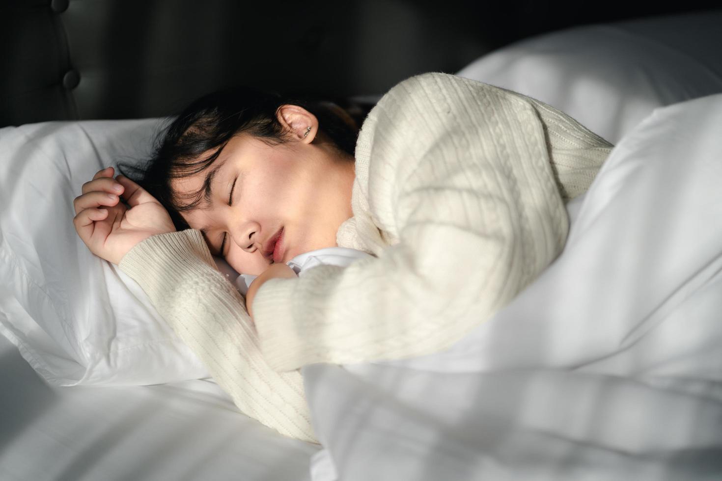 jeune femme dormant sur un lit blanc. photo