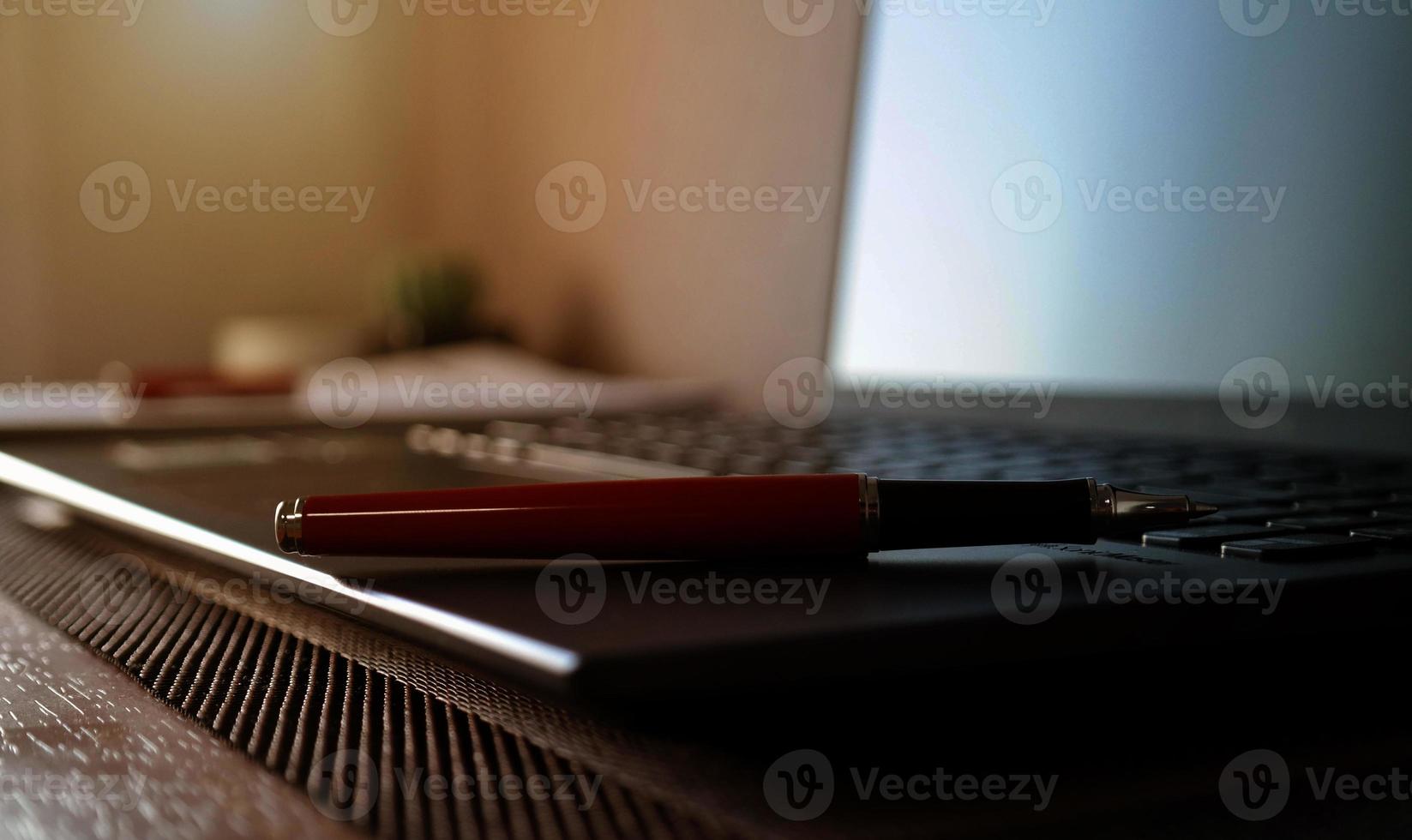stylo sur ordinateur portable flou et fournitures de bureau photo