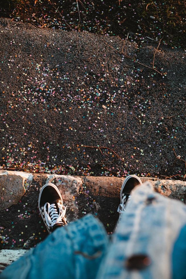 personne en jeans et baskets noires debout sur le trottoir photo