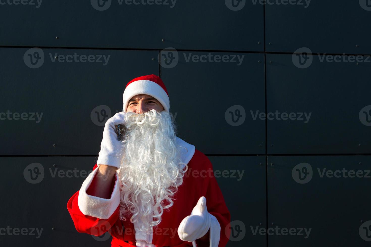 père noël moderne parlant au téléphone. commander les services d'un animateur pour les fêtes de fin d'année. salutations en ligne via internet et communication mobile, distance sociale photo