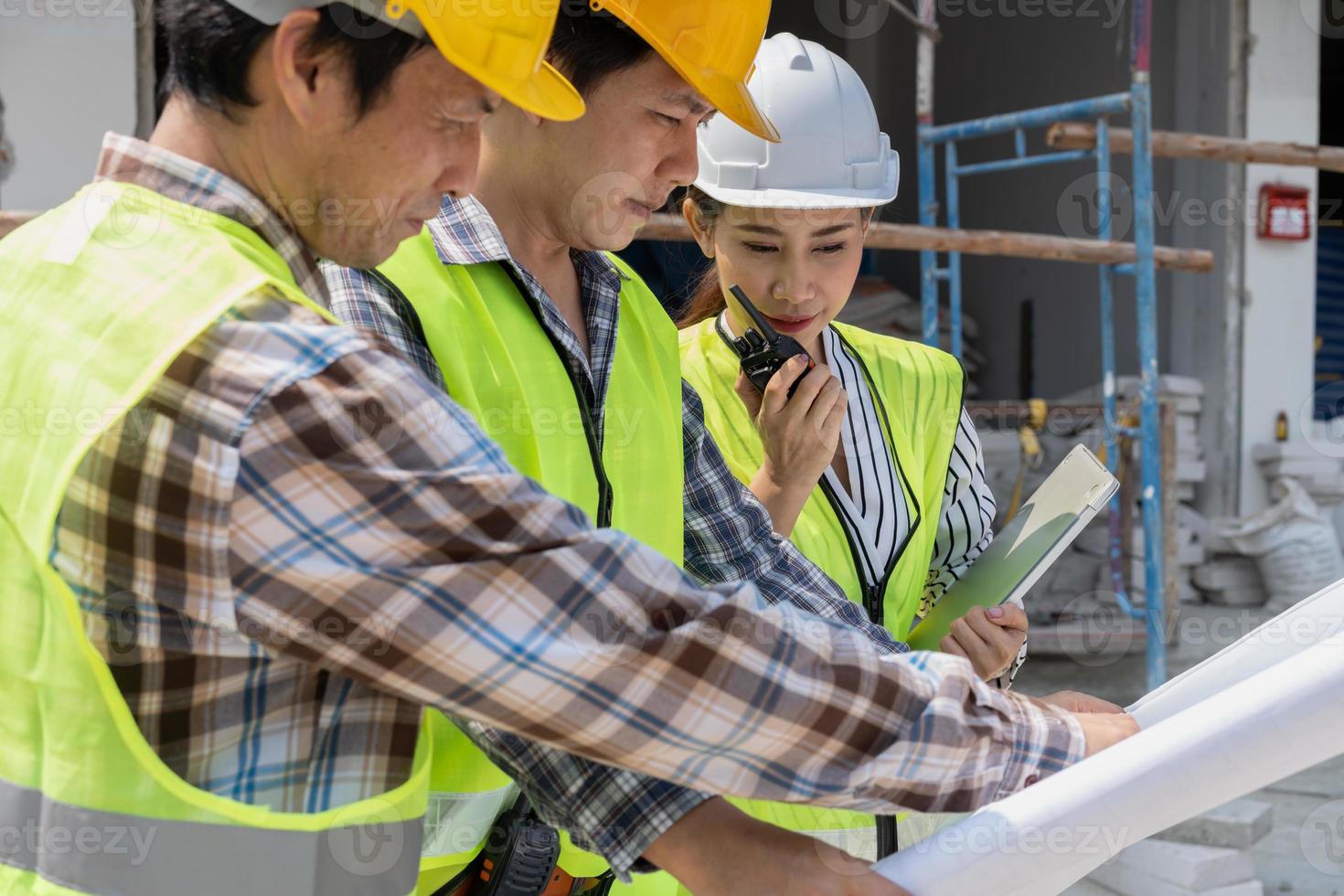 ingénieur asiatique ou jeune femme architecte met un casque pour la sécurité et parle avec un entrepreneur sur un projet d'usine de construction, concept de travail d'équipe, concept de leadership. photo