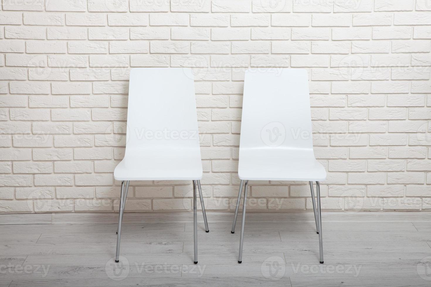 chaises blanches près du mur blanc pour les arrière-plans intérieurs ou graphiques. les chaises peuvent être utilisées pour représenter des séances d'entretien ou des salles d'attente à des fins publicitaires. photo