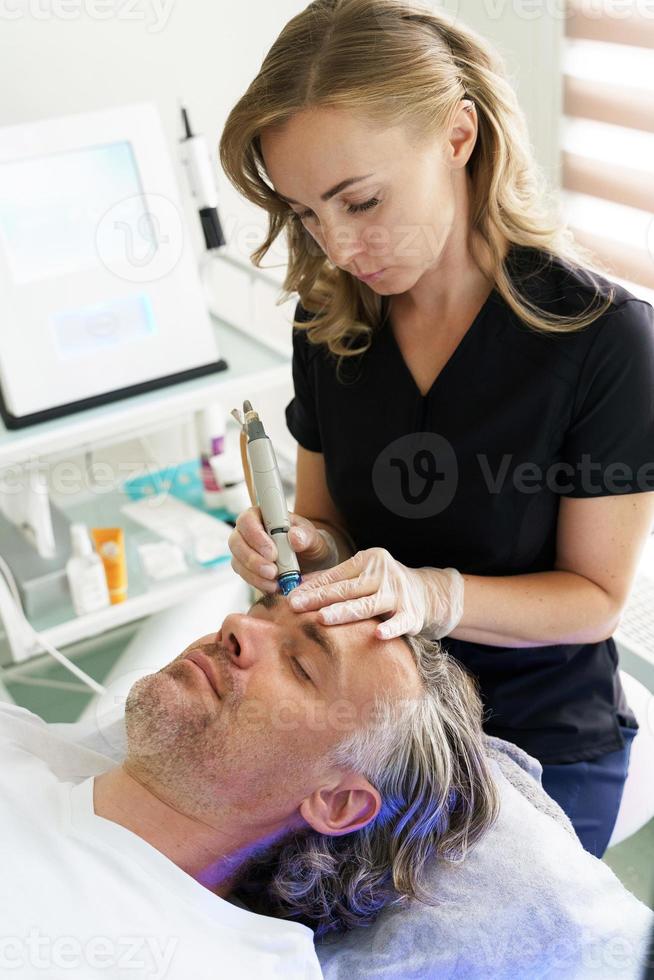 Homme d'âge moyen lors d'un nettoyage en profondeur du visage dans une clinique de cosmétologie photo