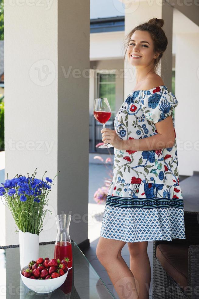 magnifique femme portant une belle robe se détendre sur le patio et boire du vin photo