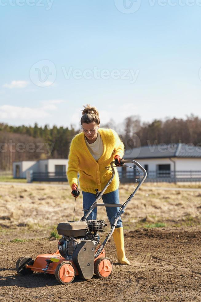 une villageoise utilise un aérateur pour la scarification et l'aération de la pelouse ou du pré photo