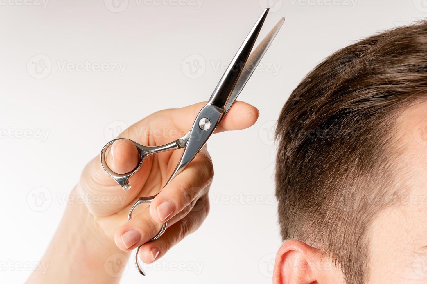 la main du coiffeur avec des ciseaux et des cheveux d'homme photo