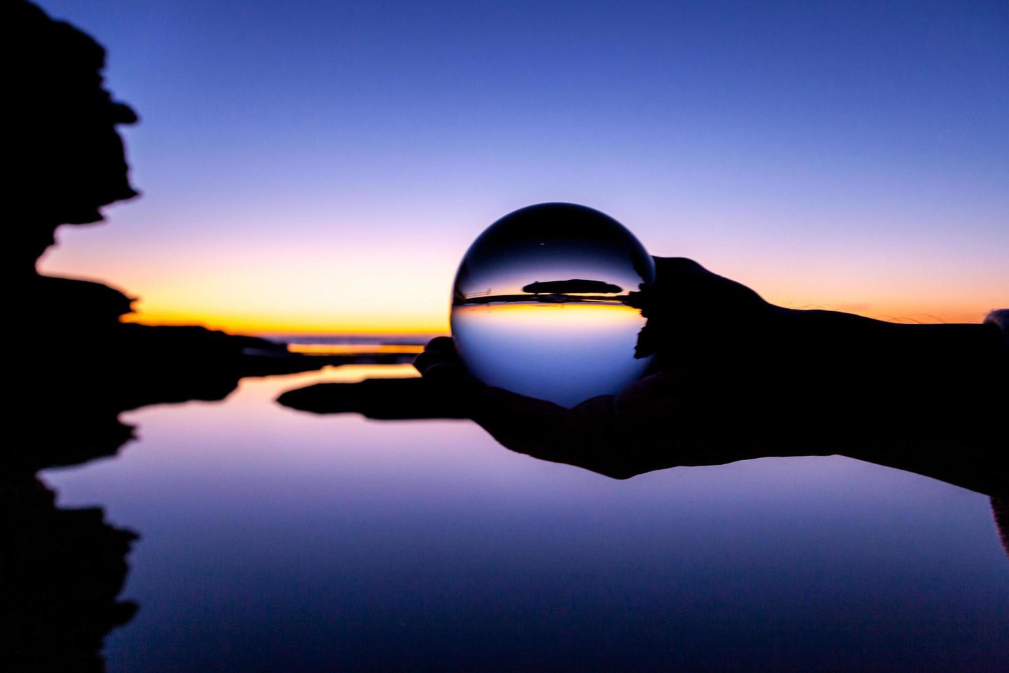 personne tenant une boule de verre au coucher du soleil photo