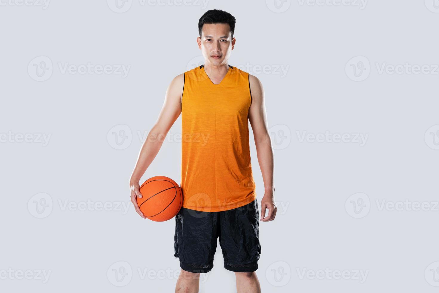 joueur de basket-ball masculin portant des vêtements de sport tenant le basket-ball sur fond blanc. photo