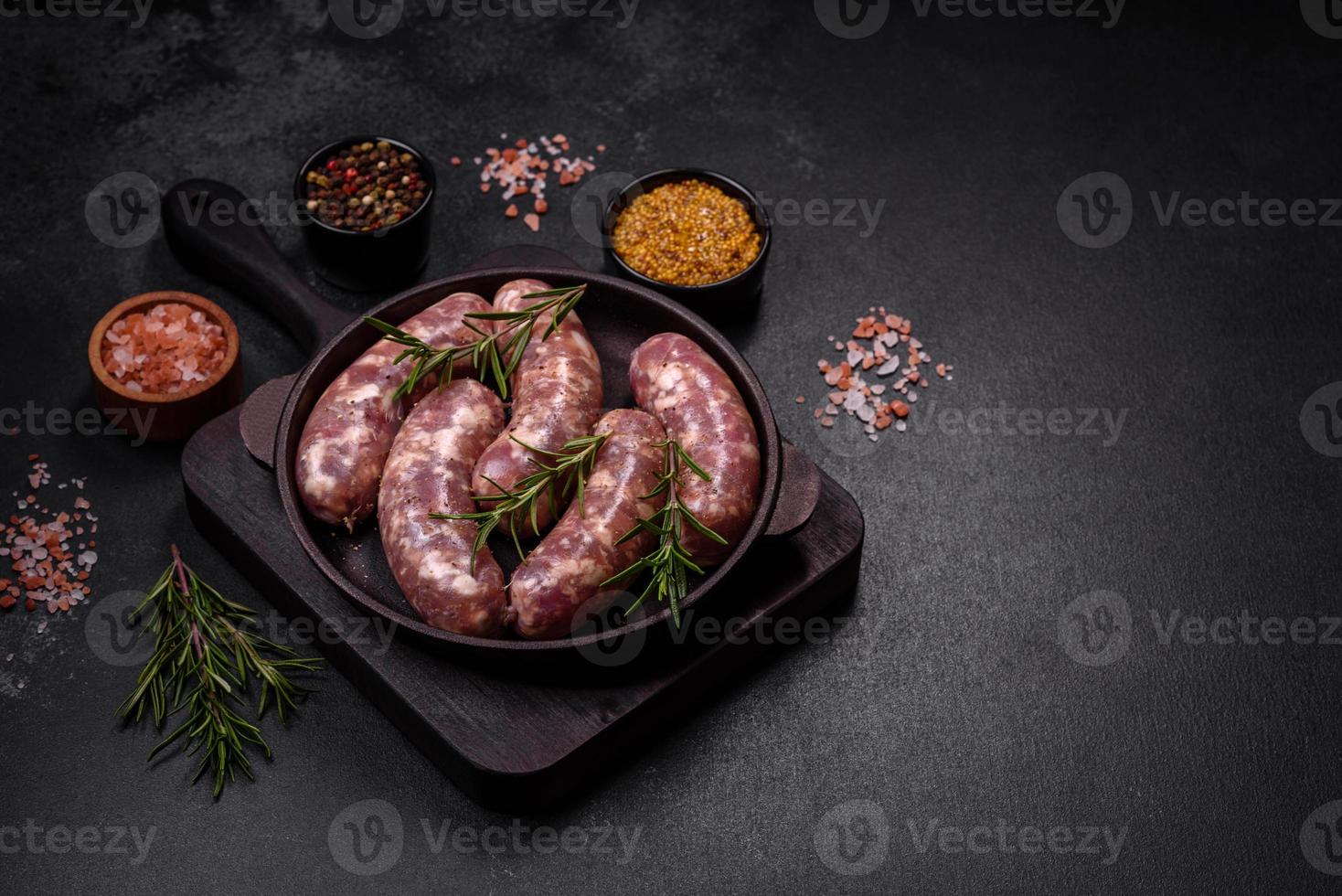 grillades de saucisses de porc crues avec épices et herbes sur une table en béton sombre photo