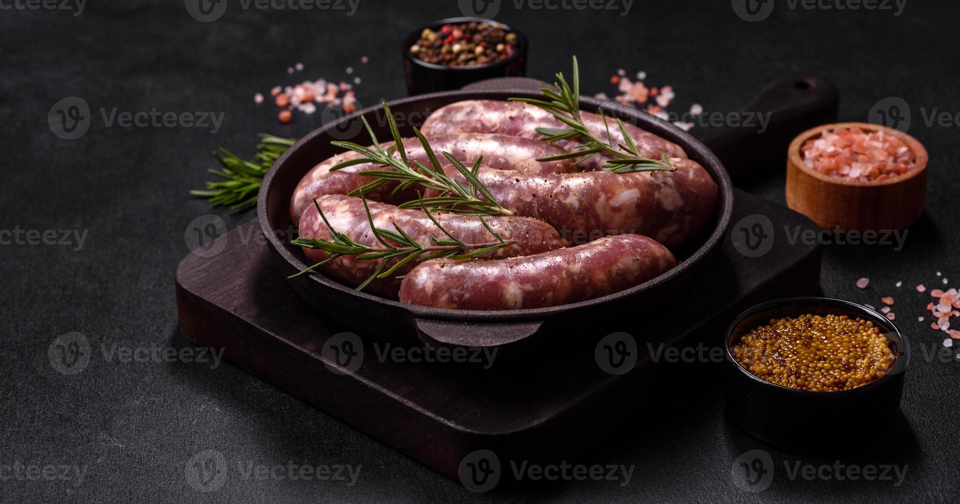 grillades de saucisses de porc crues avec épices et herbes sur une table en béton sombre photo