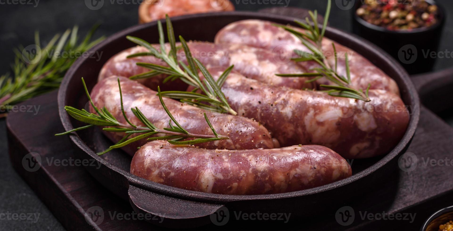 grillades de saucisses de porc crues avec épices et herbes sur une table en béton sombre photo