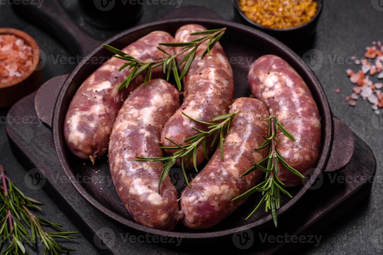 grillades de saucisses de porc crues avec épices et herbes sur une table en béton sombre photo