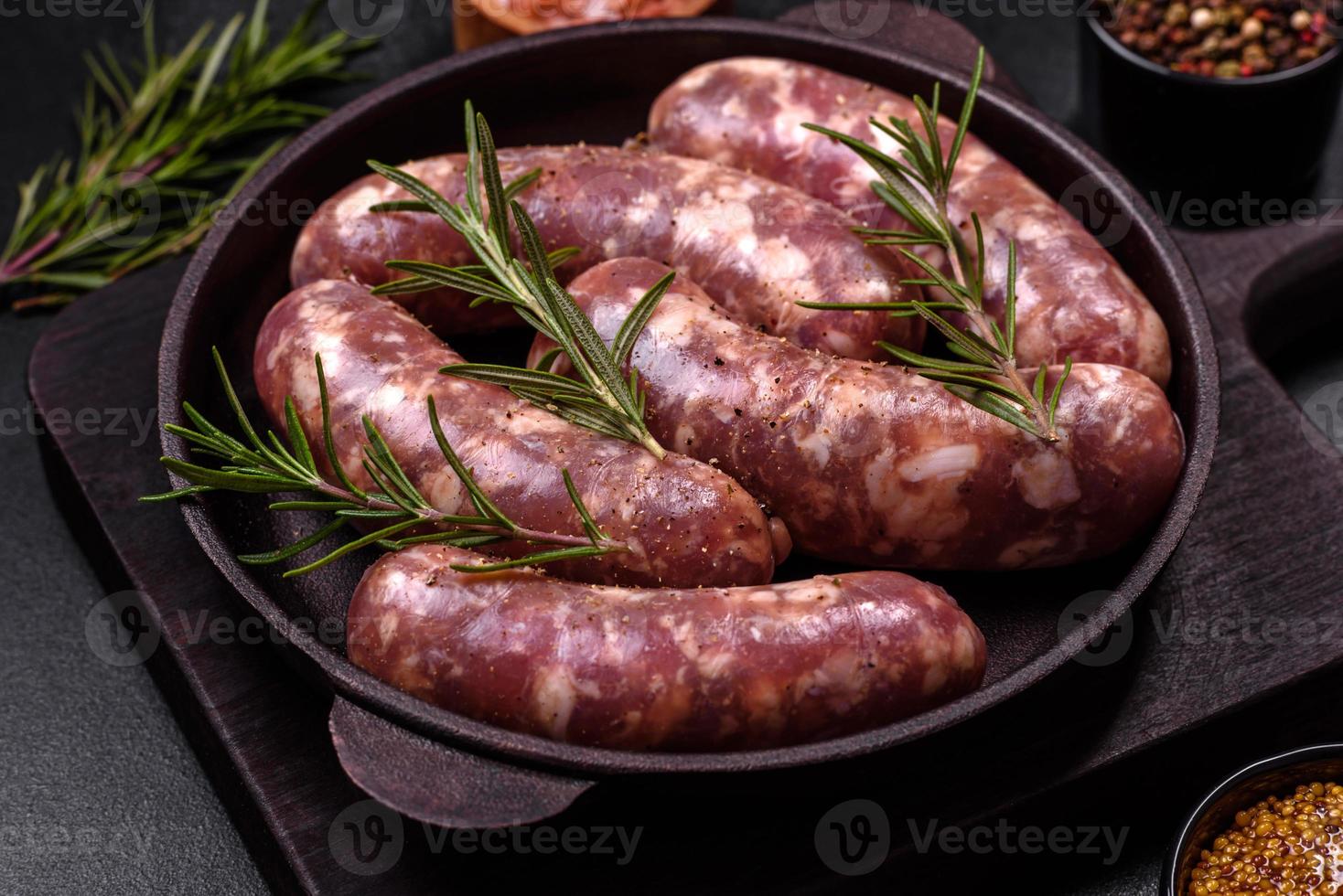 grillades de saucisses de porc crues avec épices et herbes sur une table en béton sombre photo