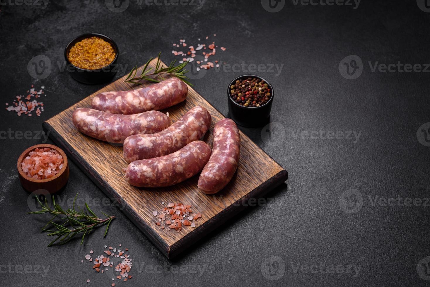 grillades de saucisses de porc crues avec épices et herbes sur une table en béton sombre photo