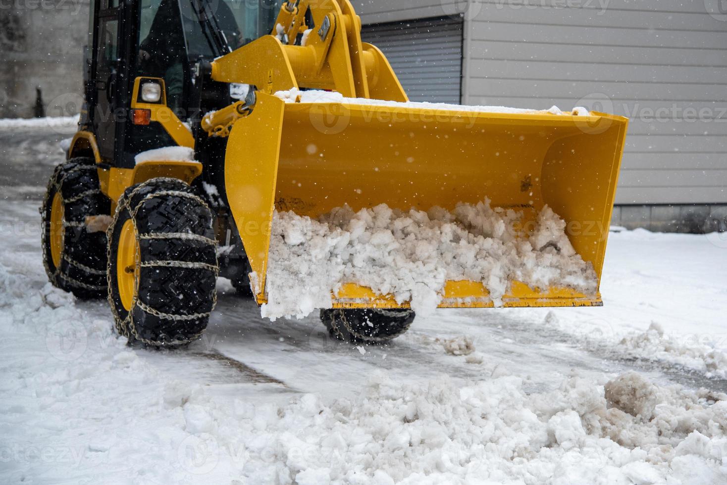 pelleteuse de tracteur avec de la neige en hiver, dégageant la neige après une tempête. photo