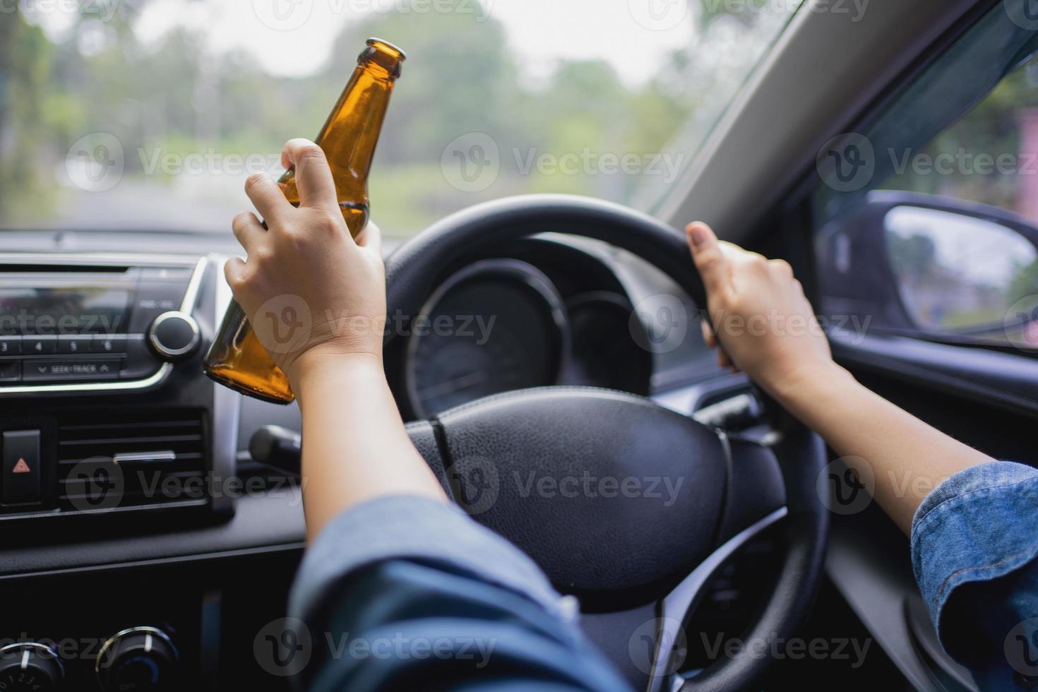 femme boit une bouteille de bière en conduisant une voiture. enfreindre la loi et boire de l'alcool au volant photo