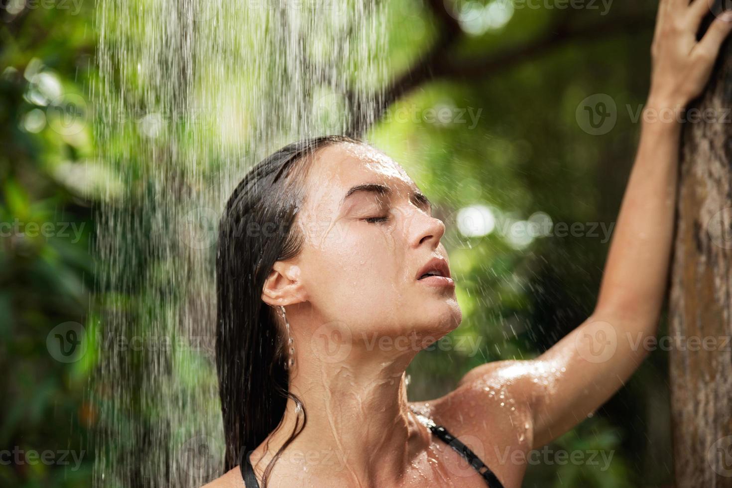 belle femme prenant une douche extérieure dans la jungle tropicale photo