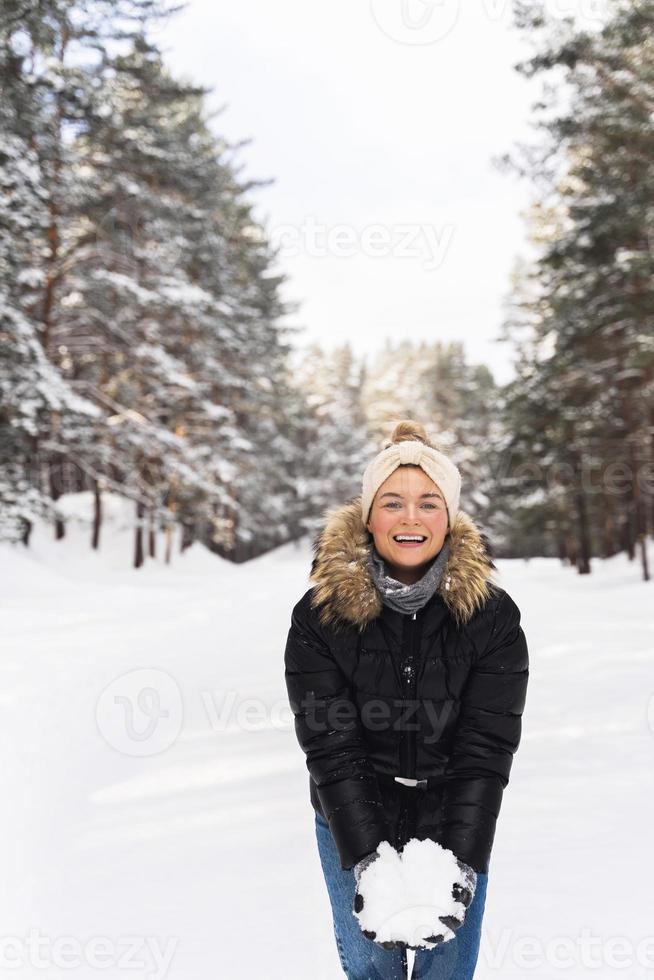 jeune femme tenant un tas de neige dans ses mains pendant sa promenade dans le parc d'hiver photo